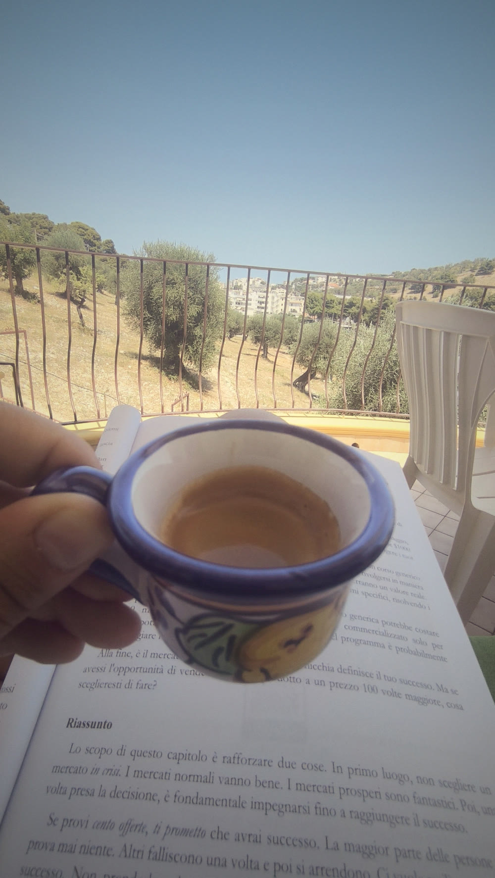 Una tazza di caffè e un libro su un terrazzo al sole